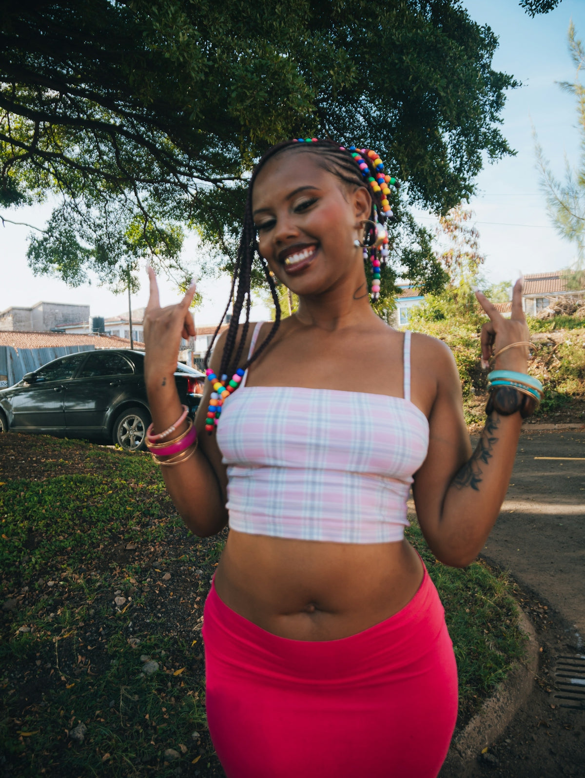 A young woman with beaded braids smiles and colorful jewelry